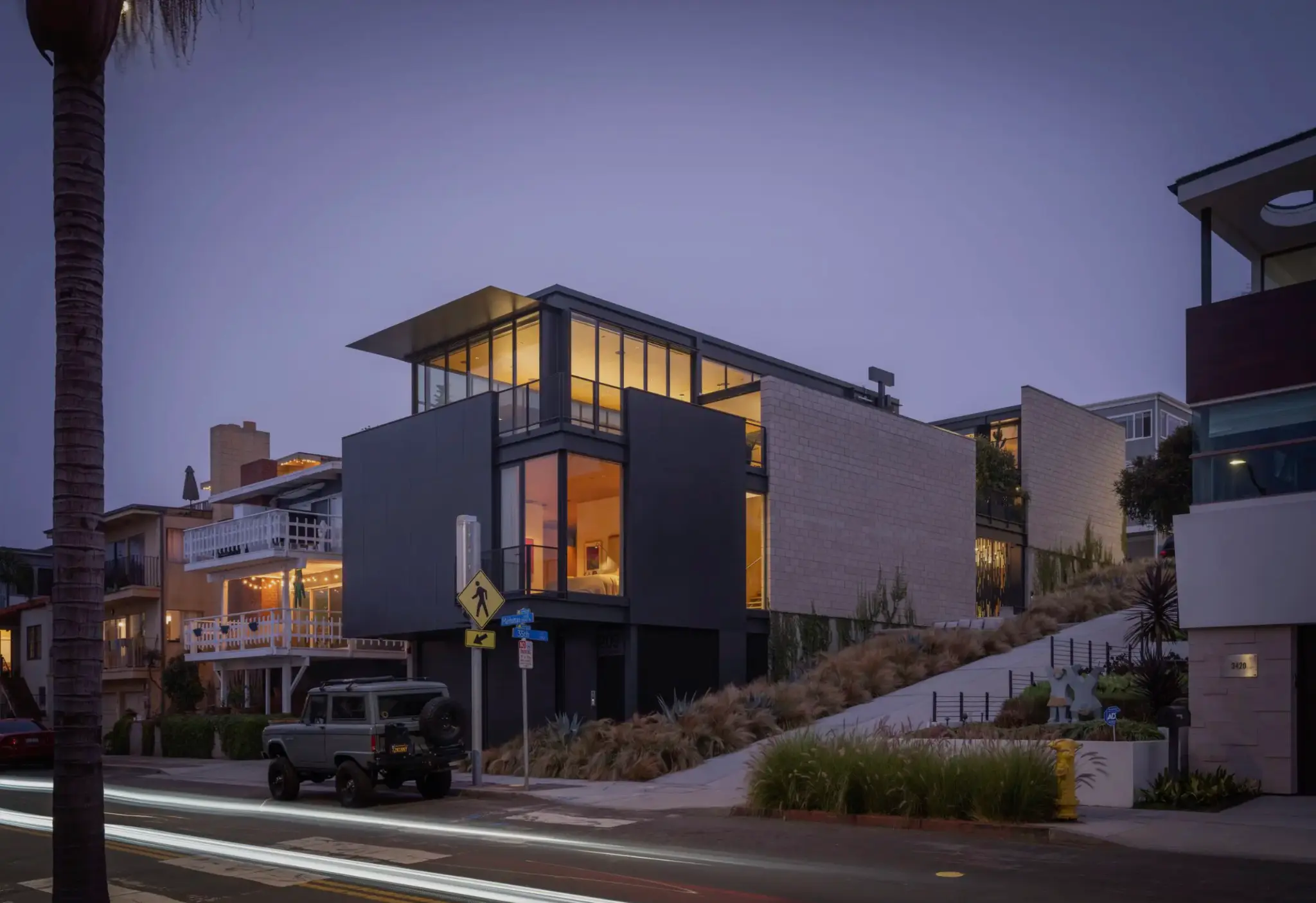 Modern architectural home with Styline minimal frame glass curtain wall system glowing at twilight on a coastal street